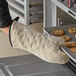 A person using 15" terry oven mitts to hold a tray of cookies.