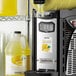 A lemonade slushy machine with a bottle of Narvon Lemonade Slushy Concentrate next to it.