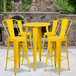 A yellow metal bar height table with yellow metal bar stools.