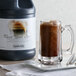 A glass mug of Narvon Root Beer Slushy with brown liquid next to a bottle of Narvon Root Beer Slushy.