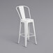 A white metal bar stool with a back and seat.