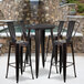 A Flash Furniture black metal bar height table with four black metal stools.