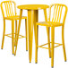 A yellow metal table with two yellow metal chairs with backrests.