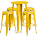 A yellow metal round bar height table with 4 square seat backless stools.