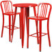 A red metal bar table with two red chairs with vertical slat backs.