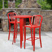 A red round bar table with a red top and two red vertical slat back chairs on a patio.