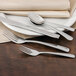 A white plate with a Walco stainless steel dinner fork and napkin on it.
