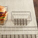 A burger and a sandwich in a stainless steel square wire basket.