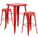 A Flash Furniture red metal bar table with two red square seat backless stools.