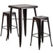 A Flash Furniture black metal bar height table with two stools.