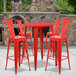 A red metal table and chair set on an outdoor patio.
