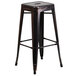 A black metal square seat backless stool on a table.