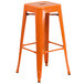 An orange metal square bar table with 2 backless stools with square orange metal seats.