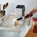 VacPak-It sous vide container with food in a bag held by tongs.