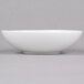 An Arcoroc white soup/cereal bowl on a gray surface.