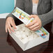 A woman opening a winter design pie box with white snowballs inside.