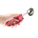 A hand holding a Zeroll #24 red universal EZ squeeze handle with a round object.