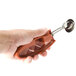 A hand using a Zeroll red ice cream scoop with a squeeze handle.