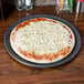 A pizza on a American Metalcraft hard coat anodized aluminum pizza pan with cheese on it.