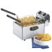 A Waring commercial countertop deep fryer with a basket of fries sitting on a counter.