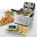 A Waring commercial countertop deep fryer with shrimp and vegetables on plates.