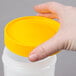 A hand holding a yellow lid on top of a Carlisle white plastic container.