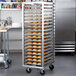 A Metro roll-in refrigerator rack with trays of bread.