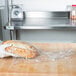 A person in a white glove holding a loaf of bread wrapped in plastic.