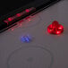 A white circular air hockey table with red and blue lights.