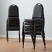 A stack of Lancaster Table & Seating black stackable banquet chairs.