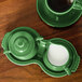 A green Fiesta sugar and creamer tray with a cup of coffee and creamer on it.