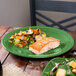 A green Fiesta® round chop plate with a piece of salmon on it.