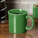 A green Fiesta china java mug with a white stripe on a wooden surface.