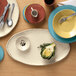 A table with Libbey Farmhouse ivory oval melamine platters, bowls, and utensils.