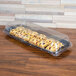 A Sabert clear plastic catering tray with a high dome lid over pastries on a table.