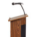 A black Oklahoma Sound microphone holder attached to a wooden podium with a gooseneck microphone.