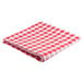 A folded red and white checkered Intedge vinyl table cover.