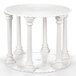 A white round table with pillars and a scalloped edge Wilton cake separator plate on it.