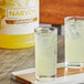 A couple of glasses with ice next to a bottle of Narvon lemonade.