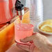 A hand pouring Narvon Pink Lemonade into a glass.