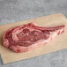 A piece of raw Warrington Farm Meats bone-in ribeye steak on a paper.
