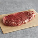 A piece of raw Warrington Farm Meats New York strip steak on a paper.