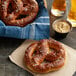A J & J SuperPretzel Bavarian Sourdough soft pretzel with salt on a napkin next to a drink.