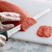 A person using a Mercer Culinary Millennia flexible salmon knife to cut salmon on a cutting board.
