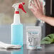A hand using Noble Chemical QuikPacks to clean a bottle on a counter.