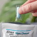 A hand holding a Noble Chemical QuikPacks concentrated glass cleaner packet.