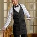 A man in a black and white pinstripe tuxedo apron holding plates.