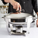 A person holding a Vollrath stainless steel silver chafer lid.