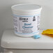 A white tub of Noble Chemical QuikPacks 0.5 oz. concentrated bowl cleaner with blue text next to a bag of blue powder.