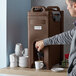 A man using a CaterGator insulated beverage dispenser to fill a coffee machine with a white mug.